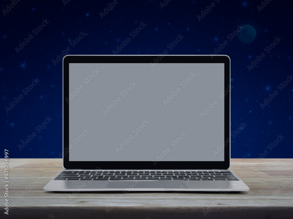 Modern laptop computer with grey blank screen on wooden table over fantasy night sky and moon Modern laptop computer with grey blank screen on wooden table over fantasy night sky and moon