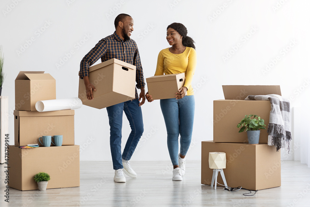 Home Relocation Concept. Joyful African American Spouses Walking With Cardboard Boxes Home Relocation Concept. Joyful African American Spouses Walking With Cardboard Boxes