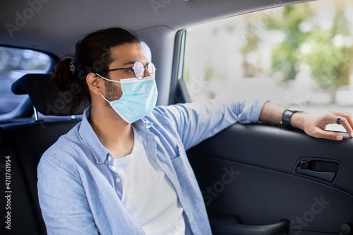 Middle-eastern man in protective face mask sitting in taxi