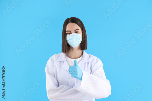 Female doctor in mask and gloves on blue background