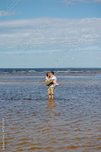 a man and a woman in love embrace and walk in nature. a man plays guitar or ukulele for his bride or wife and has fun. beautiful and young European man and woman on a romantic walk in nature enjoy