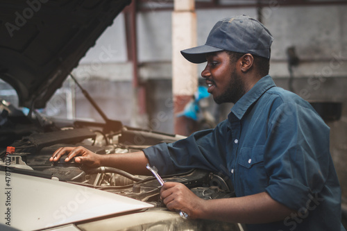 African maintenance male checking car, service via insurance system at automobile repair and check up center