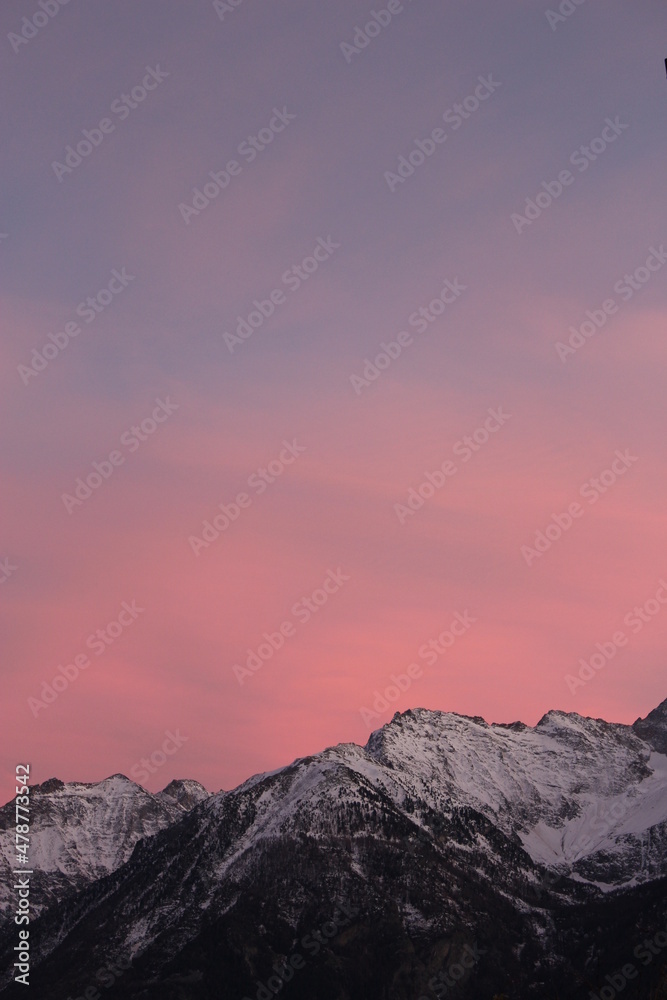 Purple and pink sunset over snow capped alpine mountains (Aosta, Italy). Stunning alpine snowy mountain winter phone, portrait screensaver or wallpaper background