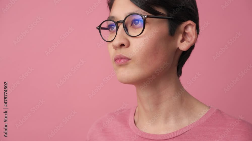 Stylish Asian man putting on eyeglasses in the pink studio Stylish Asian man putting on eyeglasses in the pink studio