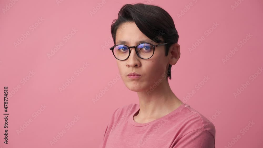 Serious Asian man in eyeglasses looking at the camera in the pink studio Serious Asian man in eyeglasses looking at the camera in the pink studio