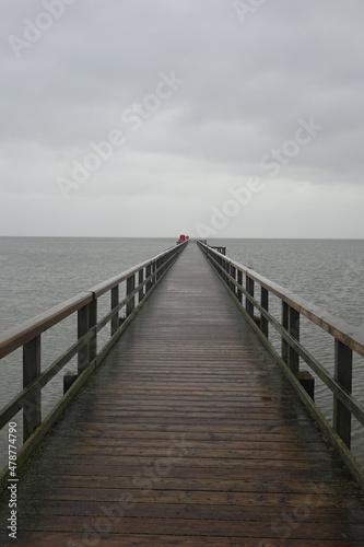 Wooden pier leading into the North Sea during high tide on a rainy day  vertical image   Burhave  Lower Saxony  Germany