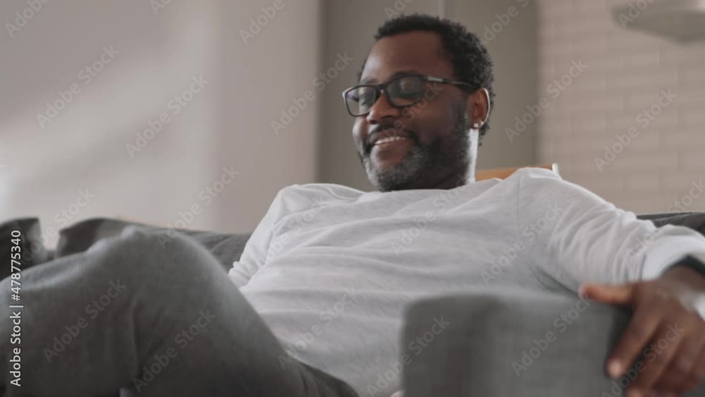 Laughing African man watching TV at home Laughing African man watching TV at home