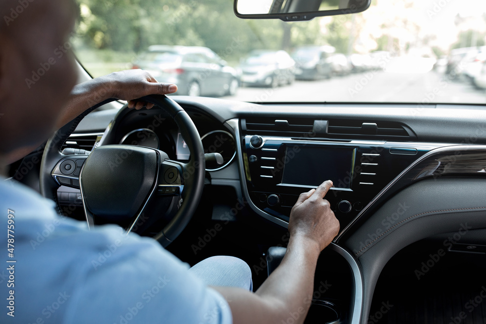 Cropped of black driver using touch pad on auto dashboard Cropped of black driver using touch pad on auto dashboard