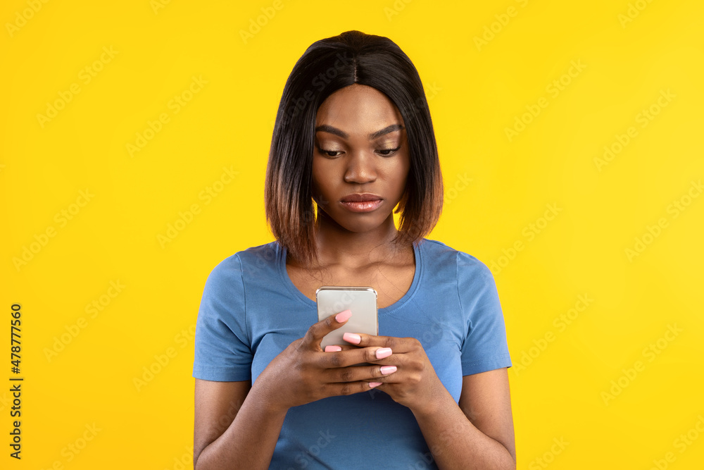 Serious African American Female Using Mobile Phone Over Yellow Background Serious African American Female Using Mobile Phone Over Yellow Background