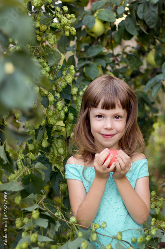 Beautiful girl holding a ripe red apple in the garden