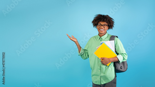 Educational offer advertisement. Positive black student showing free space for text on blue background, panorama