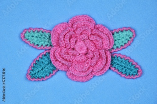 A decorative arrangement of handmade flowers and leaves on a blue crepe paper background. 