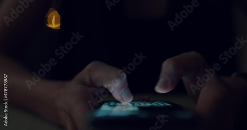 Closeup of woman type fast a message on her phone screen, text with friends or use social media in darkness. Female fingers type text on touchscreen of smartphone photo