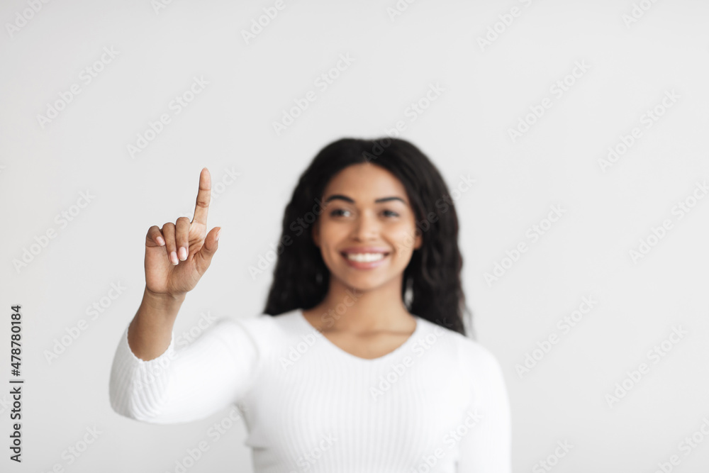 Smart home. Young african american lady pointing finger in the air pushing button on invisible screen Smart home. Young african american lady pointing finger in the air pushing button on invisible screen