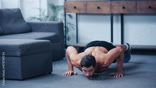 surface level view of young sportsman doing press ups on floor at home