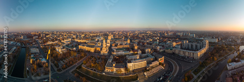 Sunny autumn cityscape, city streets traffic. Wide panoramic aerial view above river Lopan embankment, Flagpole with flag of Ukraine, Pavlivska Square, Dormition Cathedral in Kharkiv, Ukraine © Kathrine Andi