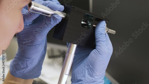 Scientist checking the condition of nebulizer needle from LC MS qTOF system using adjustment fixture and magnifier.  photo