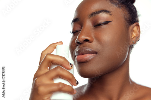 Fotografie Close-up portrait of young female fashion model using cosmetic product isolated on white studio background