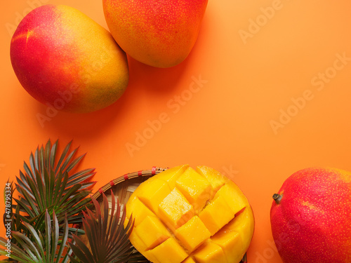 Delicious ripe mango sliced ​​ready to eat. Isolated on a colored background. Food frame, summer, tropical fruits, exotic. Space for text. Juicy mango with palm leaves. Composition with tropical fruit
