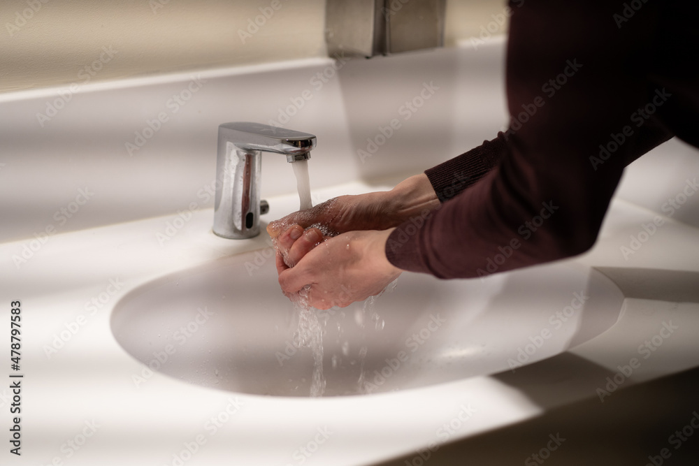 Photo of a man washing his hands under a tap with water and a special product in a shopping center. Prevention of Covid-19.