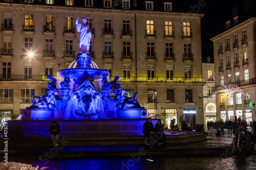 Place d'une ville avec fontaine du 19e siècle, de nuit éclairée en bleu avec personnes autour. Place Royale, Nantes photo