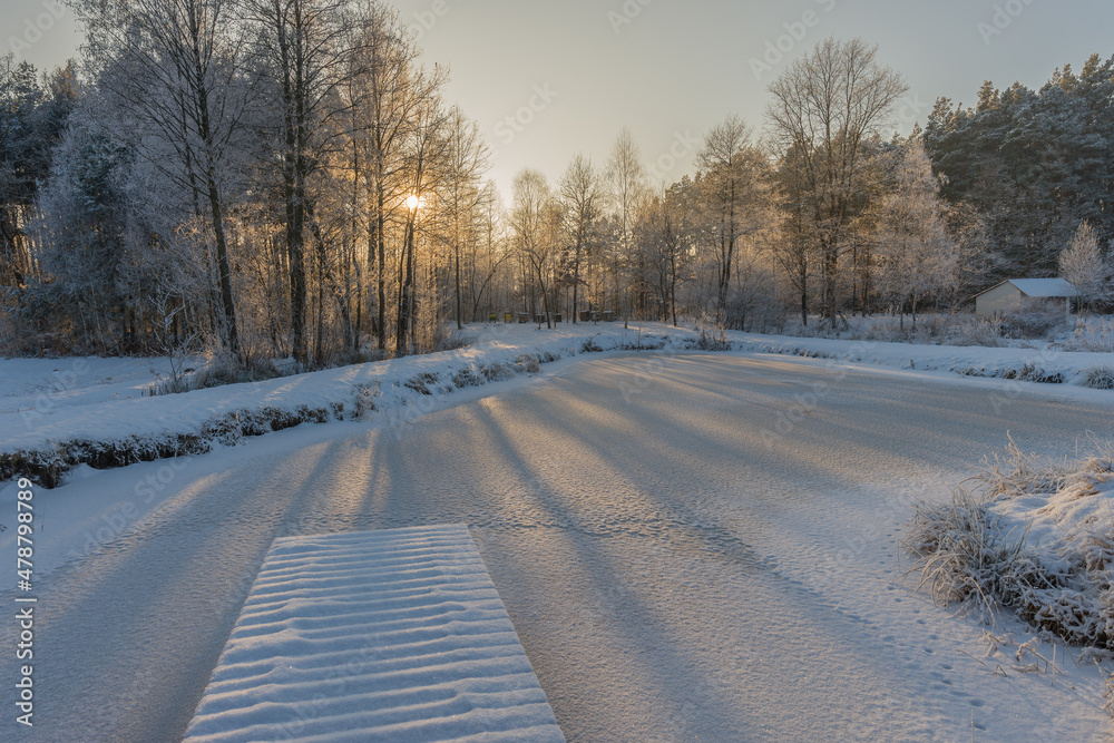 Beautiful winter scenery over the frozen lake with sunlight through trees Beautiful winter scenery over the frozen lake with sunlight through trees