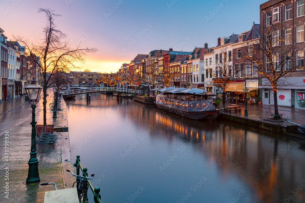 Leiden canal Oude Rijn with trees in Christmas illumination at sunrise, South Holland, Netherlands.
