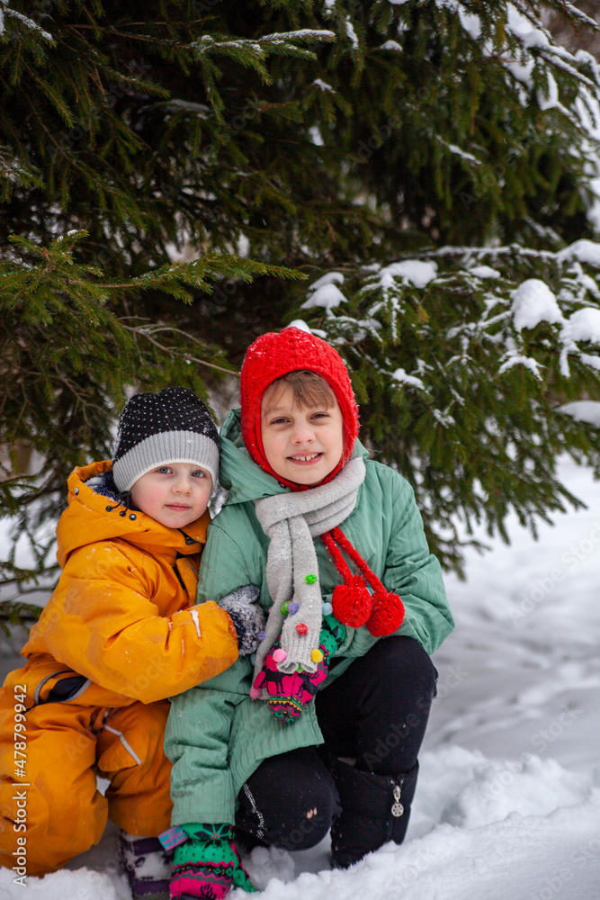 Two sisters embracing against   background of   snowy fir tree