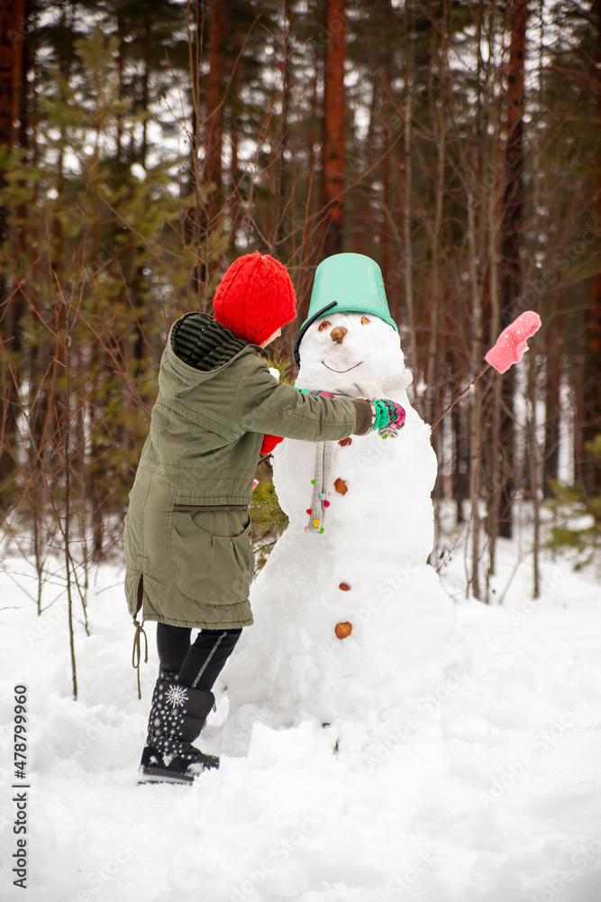 Girl of nine years old   on   winter walk near   snowman