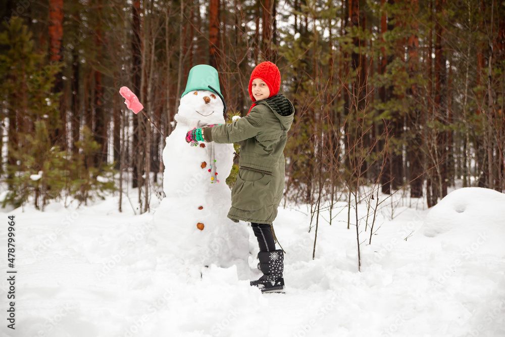 Girl of nine years old   on   winter walk near   snowman