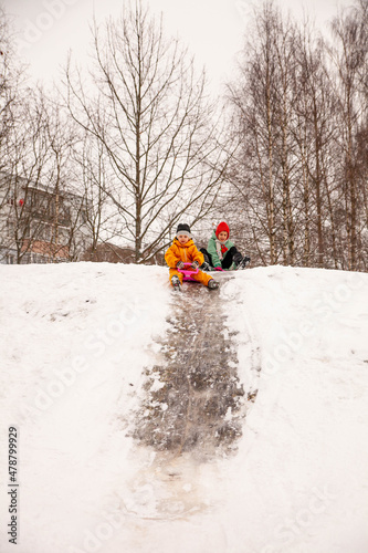 Happy children riding down   ice slide