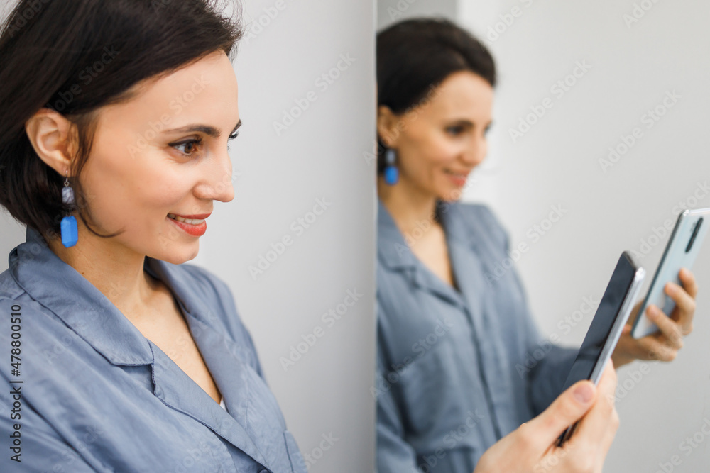 Bruinette woman in pajama working online with smartphone in hands at home. Female using phone looking at screen typing message, using telephone technology doing online job, surfing internet social Bruinette woman in pajama working online with smartphone in hands at home. Female using phone looking at screen typing message, using telephone technology doing online job, surfing internet social