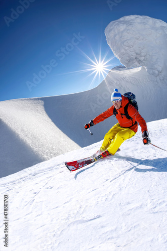 Narciarz zjazd na nartach w wysokich górach przeciw błękitne niebo