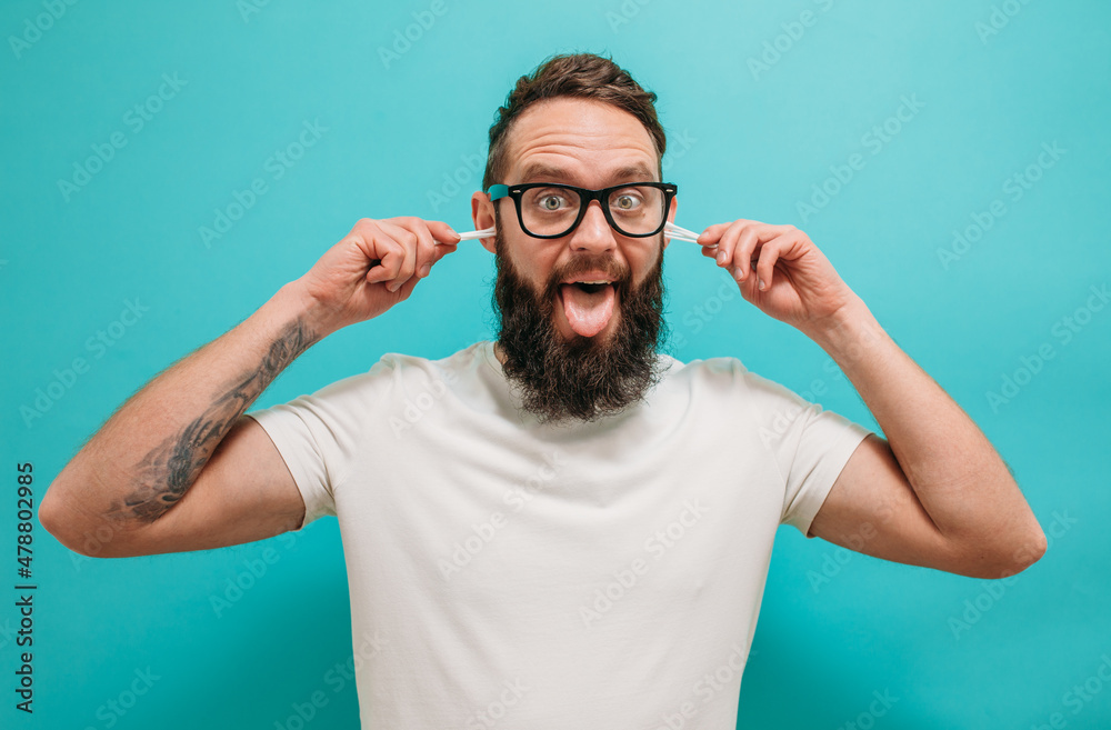 Caucasian bearded man cleaning his ears using cotton swab isolated. Removing wax from ear. Hygiene time Caucasian bearded man cleaning his ears using cotton swab isolated. Removing wax from ear. Hygiene time