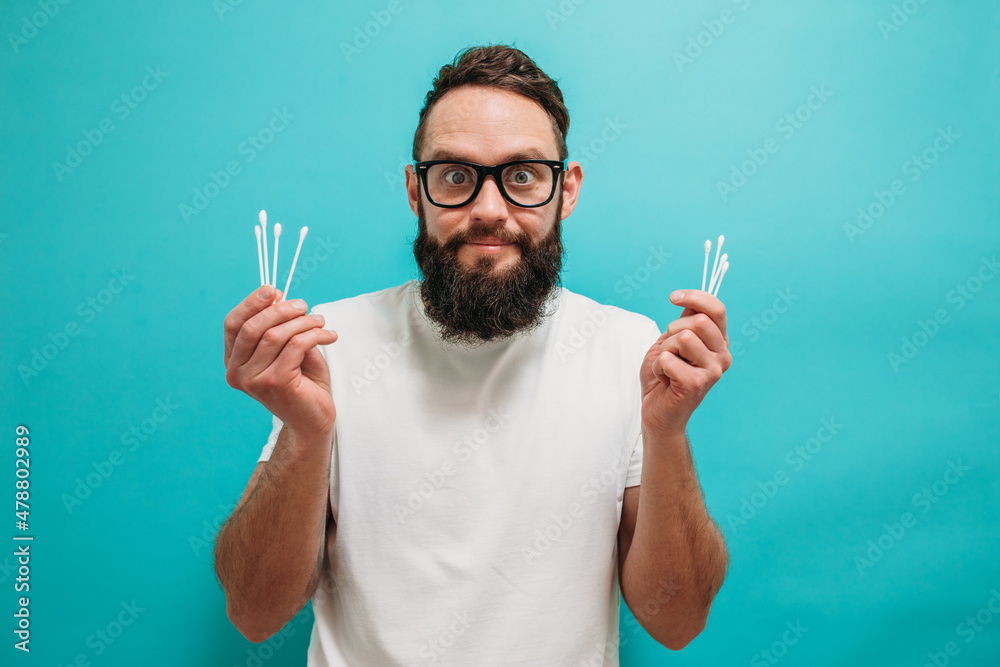 Caucasian bearded man cleaning his ears using cotton swab isolated. Removing wax from ear. Hygiene time Caucasian bearded man cleaning his ears using cotton swab isolated. Removing wax from ear. Hygiene time