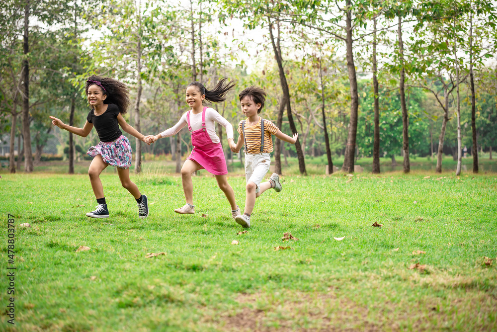Small group of a happy children run through the park in the background of grass and trees. Children's outdoor games, vacations, weekend, Children's Day Small group of a happy children run through the park in the background of grass and trees. Children's outdoor games, vacations, weekend, Children's Day