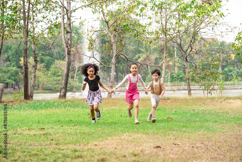 Small group of a happy children run through the park in the background of grass and trees. Children's outdoor games, vacations, weekend, Children's Day Small group of a happy children run through the park in the background of grass and trees. Children's outdoor games, vacations, weekend, Children's Day