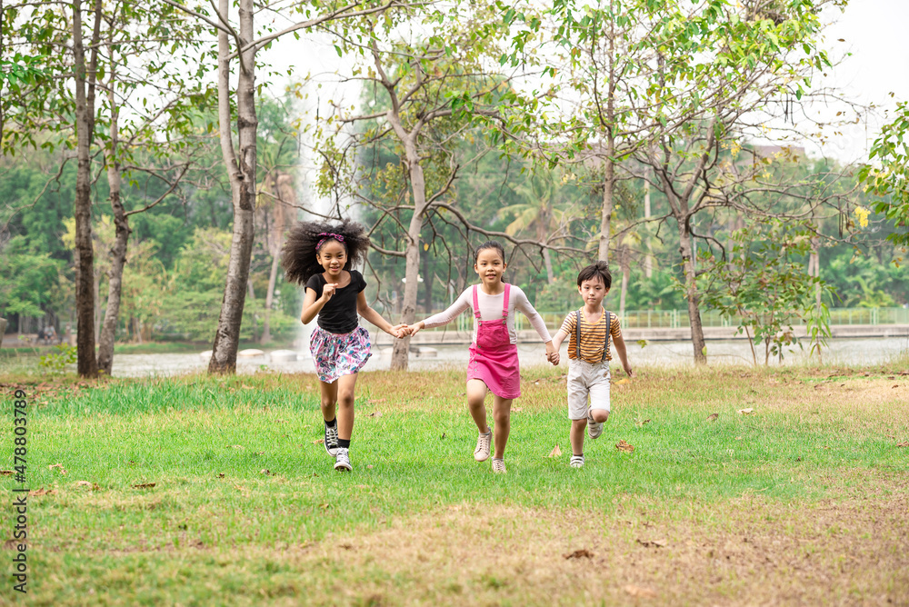 Small group of a happy children run through the park in the background of grass and trees. Children's outdoor games, vacations, weekend, Children's Day