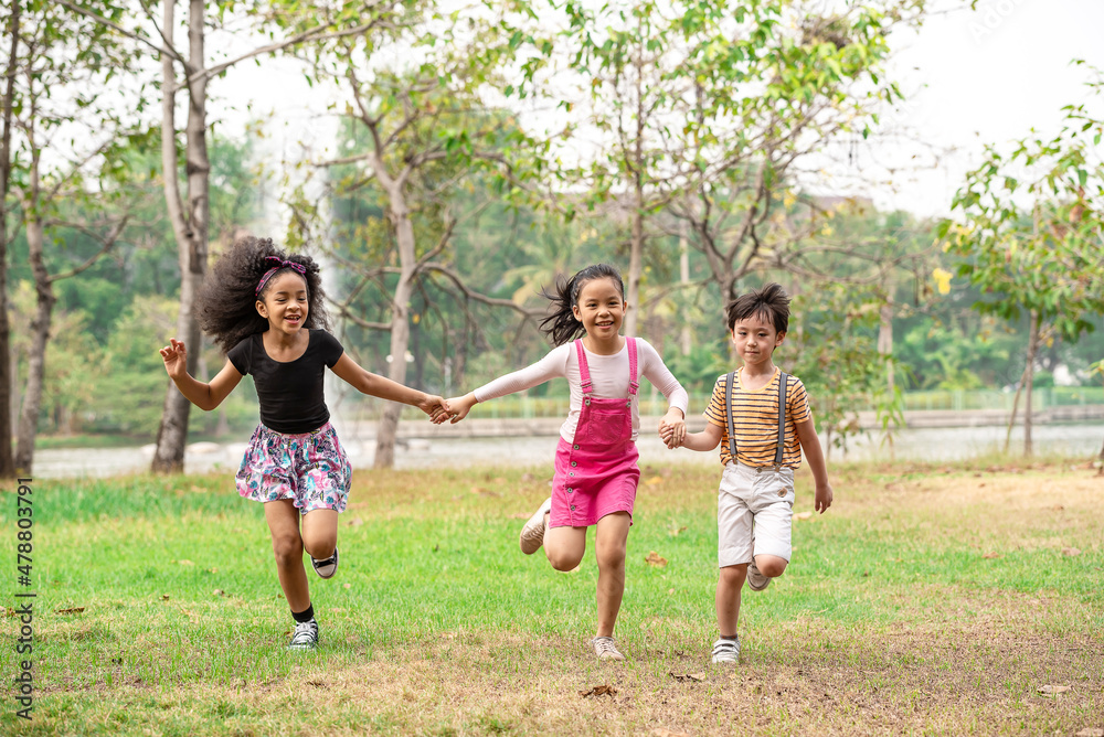 Small group of a happy children run through the park in the background of grass and trees. Children's outdoor games, vacations, weekend, Children's Day Small group of a happy children run through the park in the background of grass and trees. Children's outdoor games, vacations, weekend, Children's Day