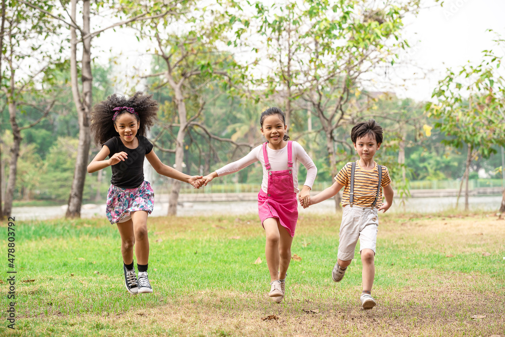 Small group of a happy children run through the park in the background of grass and trees. Children's outdoor games, vacations, weekend, Children's Day Small group of a happy children run through the park in the background of grass and trees. Children's outdoor games, vacations, weekend, Children's Day