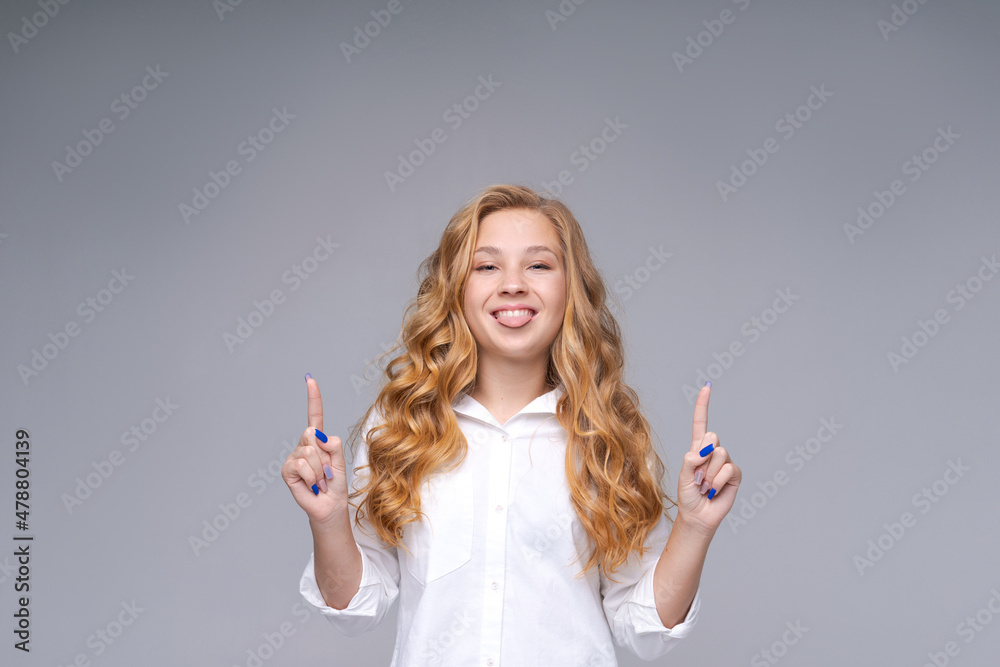 Photo positive girl with blond hair in white shirt shows thumb up an empty space option with a discount on a light background. Caucasian young woman happily advertise Photo positive girl with blond hair in white shirt shows thumb up an empty space option with a discount on a light background. Caucasian young woman happily advertise