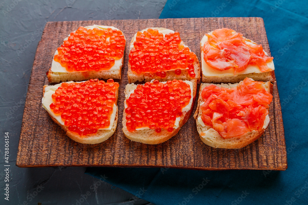 Bruschetta with red caviar on a handmade wooden board. Bruschetta with red caviar on a handmade wooden board.
