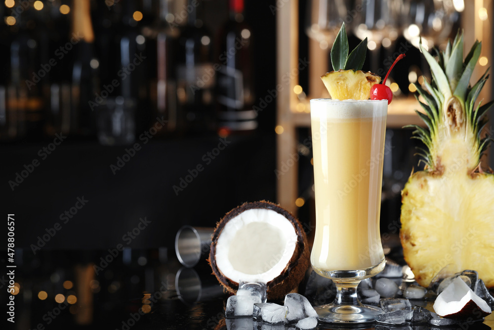 Tasty Pina Colada cocktail and ingredients on bar countertop, space for text Tasty Pina Colada cocktail and ingredients on bar countertop, space for text