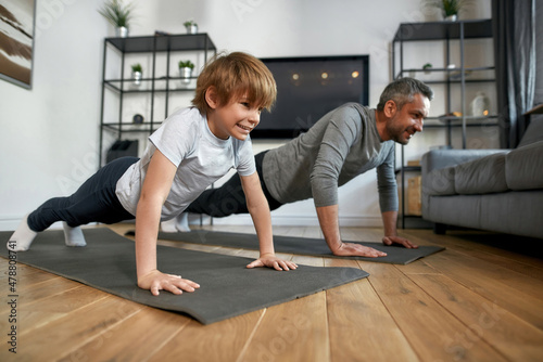Happy sporty father and son train together at home