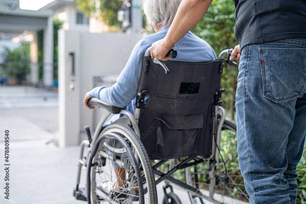Obraz premium Caregiver help and care Asian senior or elderly old lady woman patient sitting on wheelchair at nursing hospital ward, healthy strong medical concept