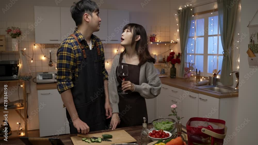 asian male stops preparing for valentine’s day dinner and comforts his hungry girlfriend as she is acting in a cutesy way with wine glass in the kitchen at home asian male stops preparing for valentine’s day dinner and comforts his hungry girlfriend as she is acting in a cutesy way with wine glass in the kitchen at home
