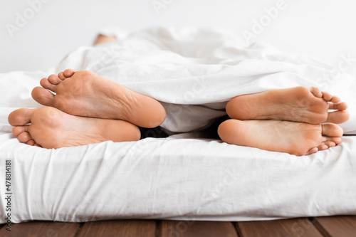 Closeup Of Couple's Feet Under Blanket Lying Back-To-Back In Bed