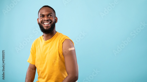 Obraz na plátne Cheerful vaccinated black man with plaster bandage on his shoulder after covid-1