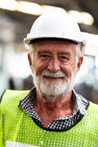 Portrait of senior engineering architect builder wearing protective hardhat working at Metal lathe industrial manufacturing factory. Engineer Operating lathe Machinery. Elderly people