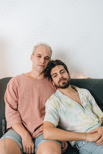 Gay happy couple sitting on sofa